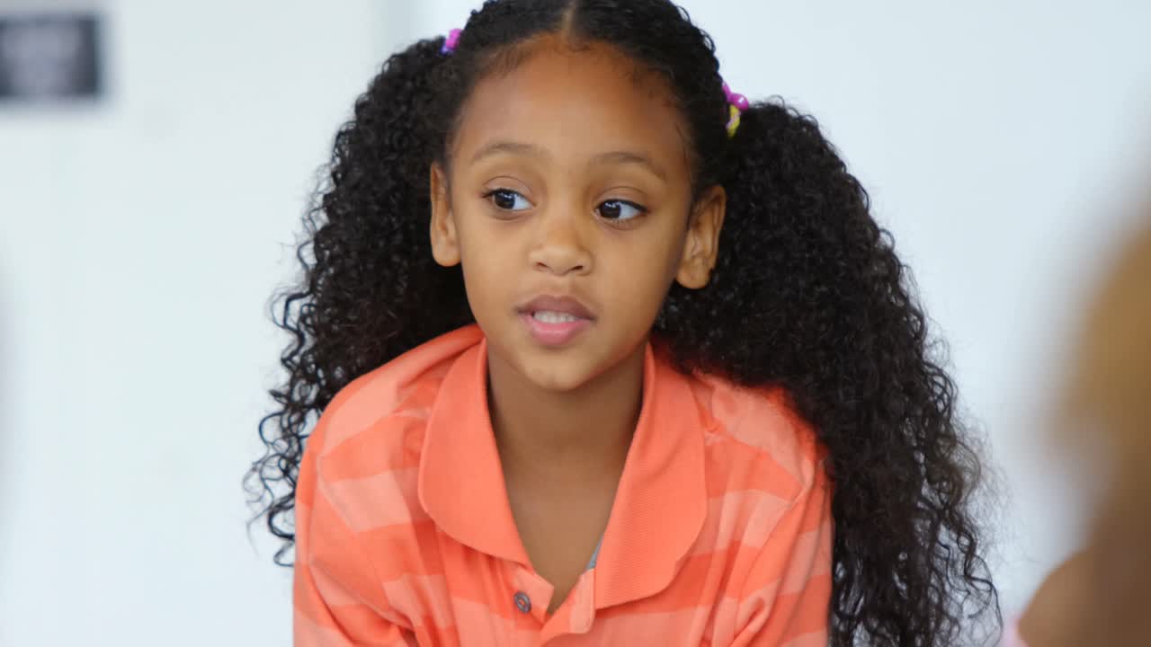 Front view of African American schoolgirl teaching schoolkids in the classroom 4k