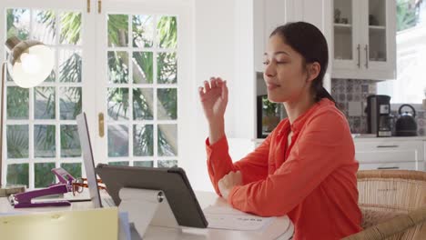 Portrait-of-biracial-woman-sitting-at-table-and-working-with-laptop