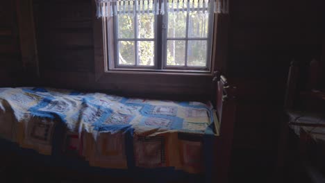 a pan shot of the inside of an old wooden cottage, showcasing a rustic show room with a bed, perfect for showcasing rural living, country lifestyle, and vintage interior design