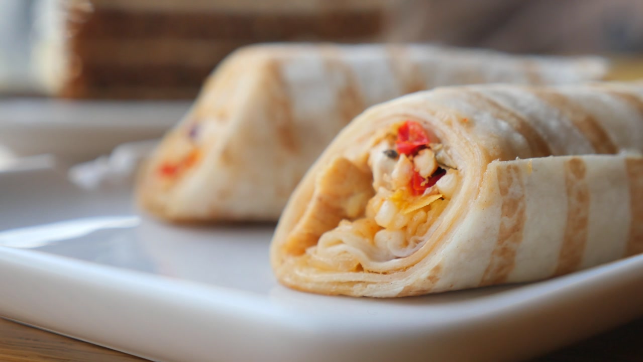 Close-up of Grilled Chicken and Vegetable Wraps on a White Plate