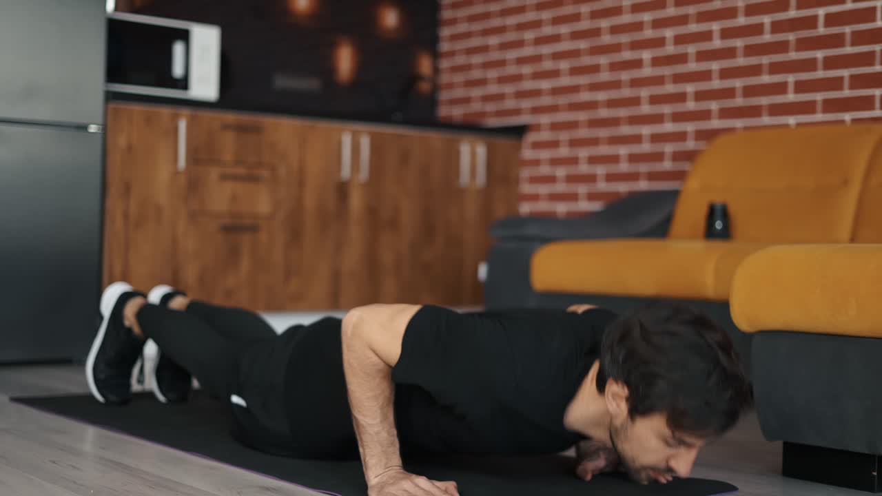 un hombre europeo hace ejercicio, haciendo flexiones, acostado en una alfombra en casa