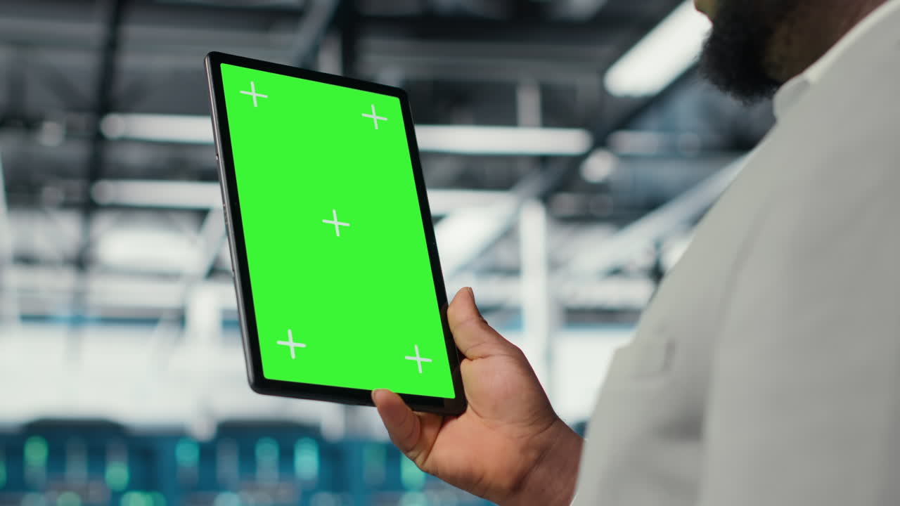 Technician upgrading equipment in data center using green screen tablet