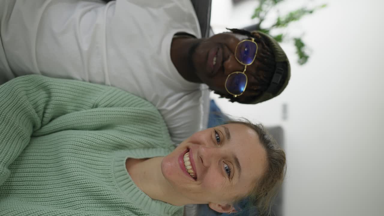 una pareja interracial feliz haciendo una llamada de video por la cámara frontal del teléfono celular, saludando con la mano