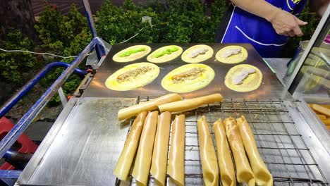 vendor prepares mini pancake rolls in bangkok, thailand