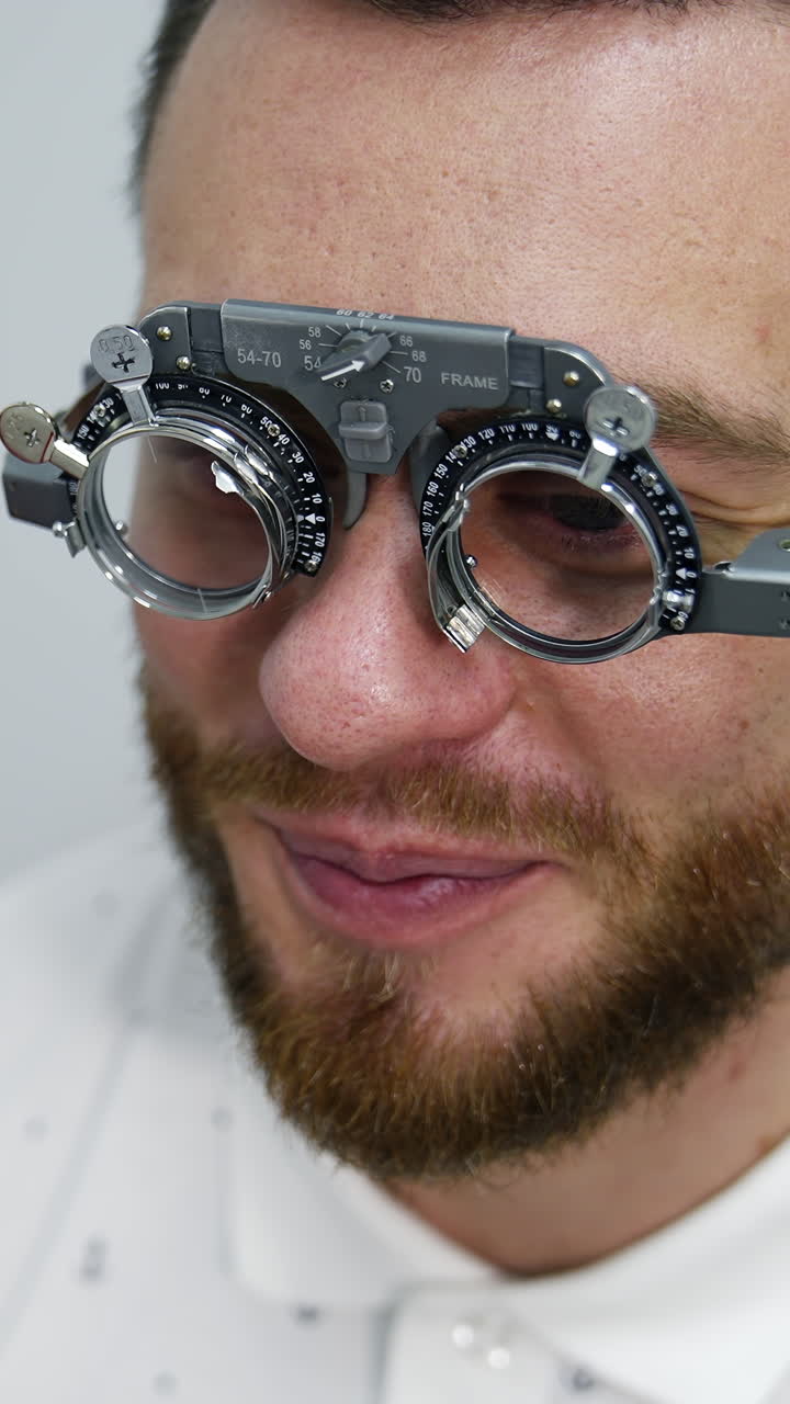 Handsome man at ophthalmology clinic. Special testing glasses with replacable lenses for vision correction on a male patient. Vertical video