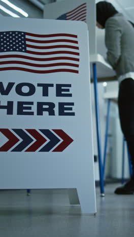 vote here sign on the floor. diverse american citizens vote in booths in polling station office. national elections day in the united states. political races of us presidential candidates. civic duty.