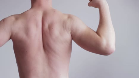 hombre adulto sin camisa flexionando los hombros hacia atrás, vista estática del primer plano trasero