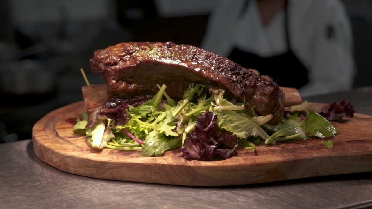 costilla de ternera asada sobre verduras en tablero tallado en madera en la cocina de un restaurante comercial, hd