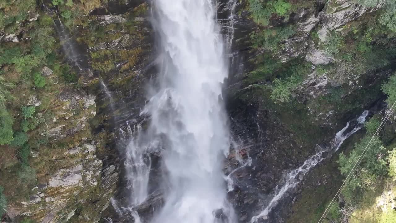 panorámica aérea desde el lado de una cascada alta alojada en las montañas