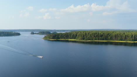 aerial view tracking a boat driving on lake saimaa, sunny, summer day in finland