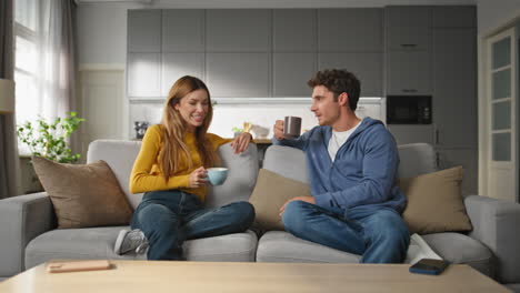 happy lovers drinking coffee talking together at home. laughing family chilling