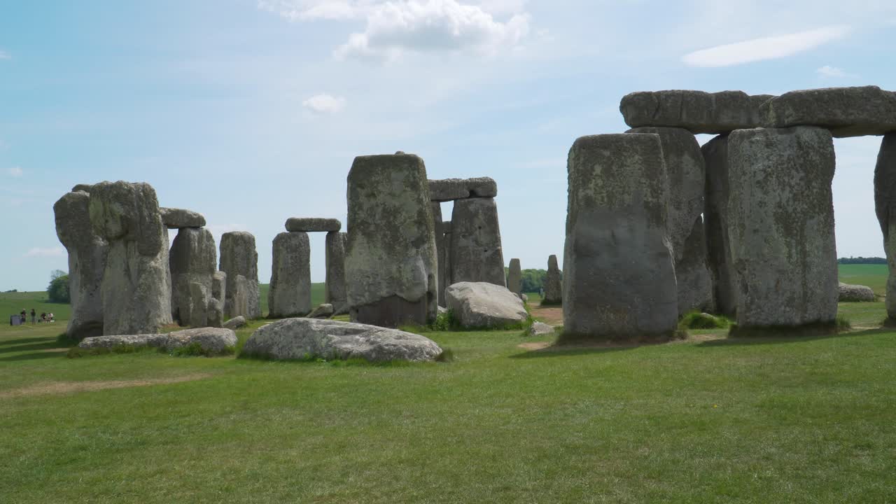 Close up view to the Stonehenge a prehistoric megalithic structure on Salisbury plain in Wiltshire England. People moving in the background, steady camera and blue sky on a sunny day.