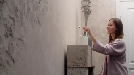 woman lighting candles in a cozy room