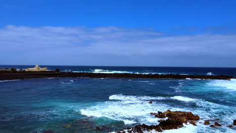 Aerial-shot-behind-the-sea-waves-and-surfers-in-the-distance