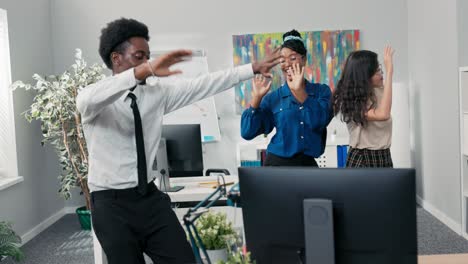 dance at work, office, break from duties, company party, two girls and a man in a shirt and tie dancing together, fooling around, laughing, smiling, relieving stress, music playing from the computer
