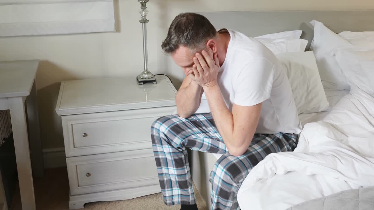 Homem sentado na cama depois de acordar no quarto 4k