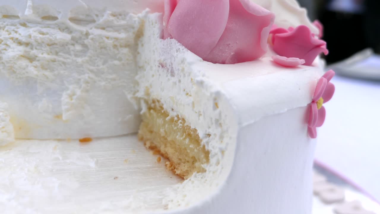 Close up turning shot of the remaining part of a delicious cake. It is a cream cake with sugar and marzipan flowers on top.