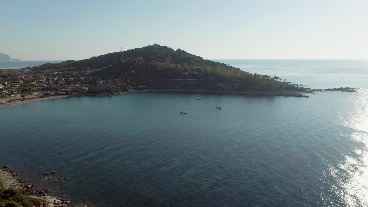 cerdeña, italia, costa de arbatax, drones vuelan sobre la bahía del mar entre formaciones rocosas de acantilados durante un día soleado de verano con velero