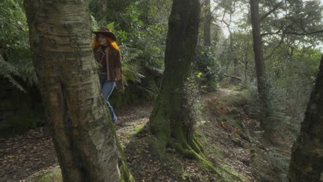 mujeres pelirrojas caminando desde detrás de un árbol a lo largo de un sombrío camino de bosque inglés