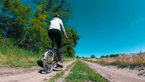 young woman riding vintage bicycle along a rural road in a village