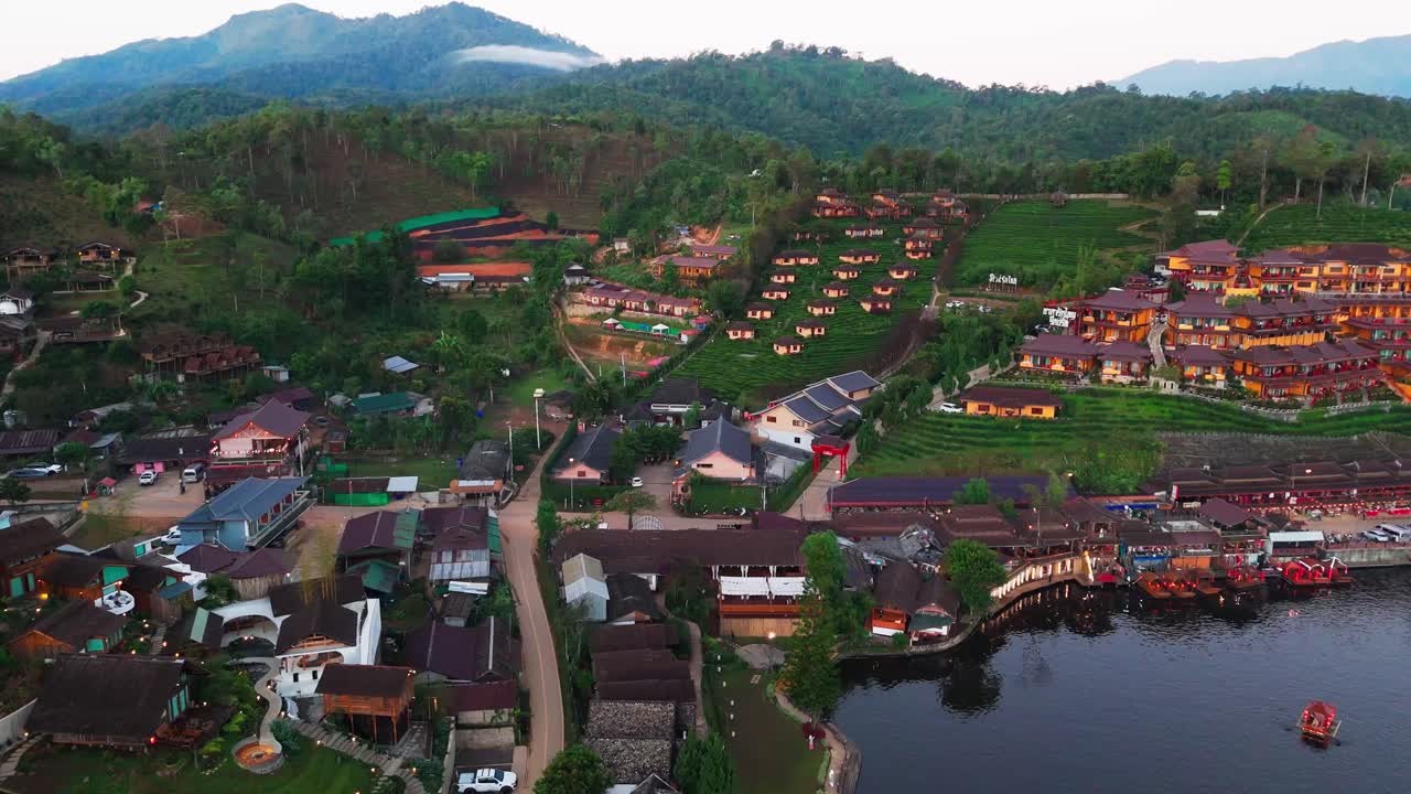 Voo aéreo sobre a vila de montanha Ban Rak Thai, lago, vale cercado por colinas e plantações de chá em Mae Hong Son.