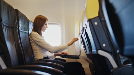 mujer de negocios trabajando en una computadora portátil en un avión