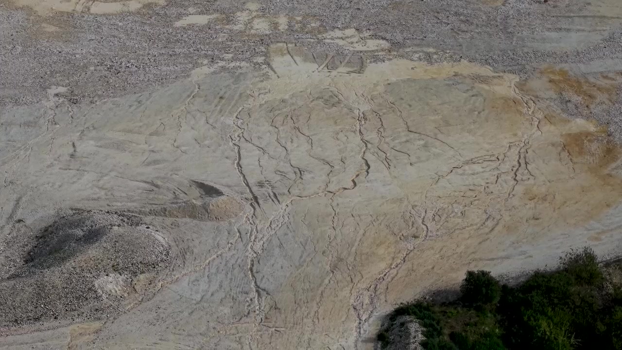 Discesa di drone nella cava di sabbia e ghiaia di Essendon che sfiora dune texturizzate e linee di erosione, creando un aspetto di superficie lunare e un'atmosfera da pianeta alieno, paesaggio industriale a Victoria, Australia