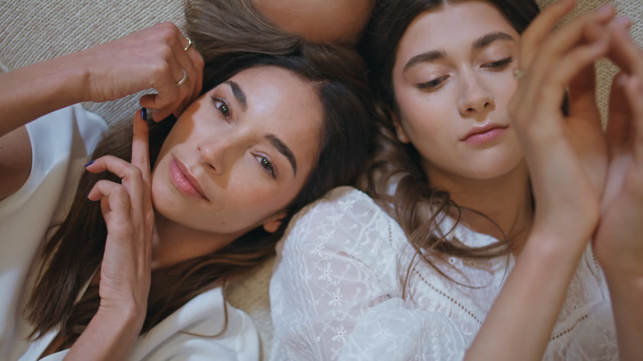 Primo piano di donne attraenti in posa insieme. Modelle di moda in vista dall'alto con le mani in movimento.