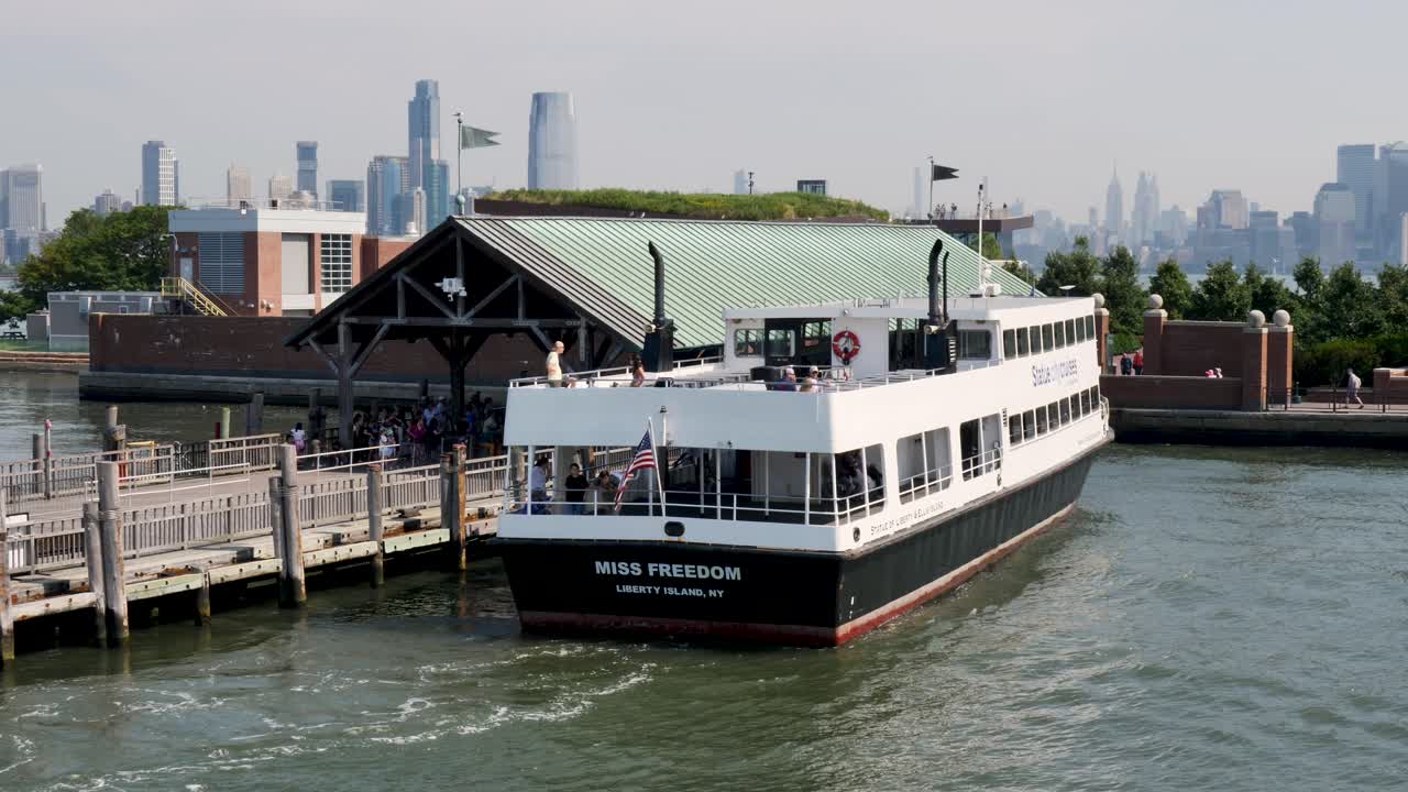 Slow motion landscape of ferry boat docked at harbour wharf with tourists for sightseeing tour Statue of Liberty New York City Staten Island USA America travel tourism