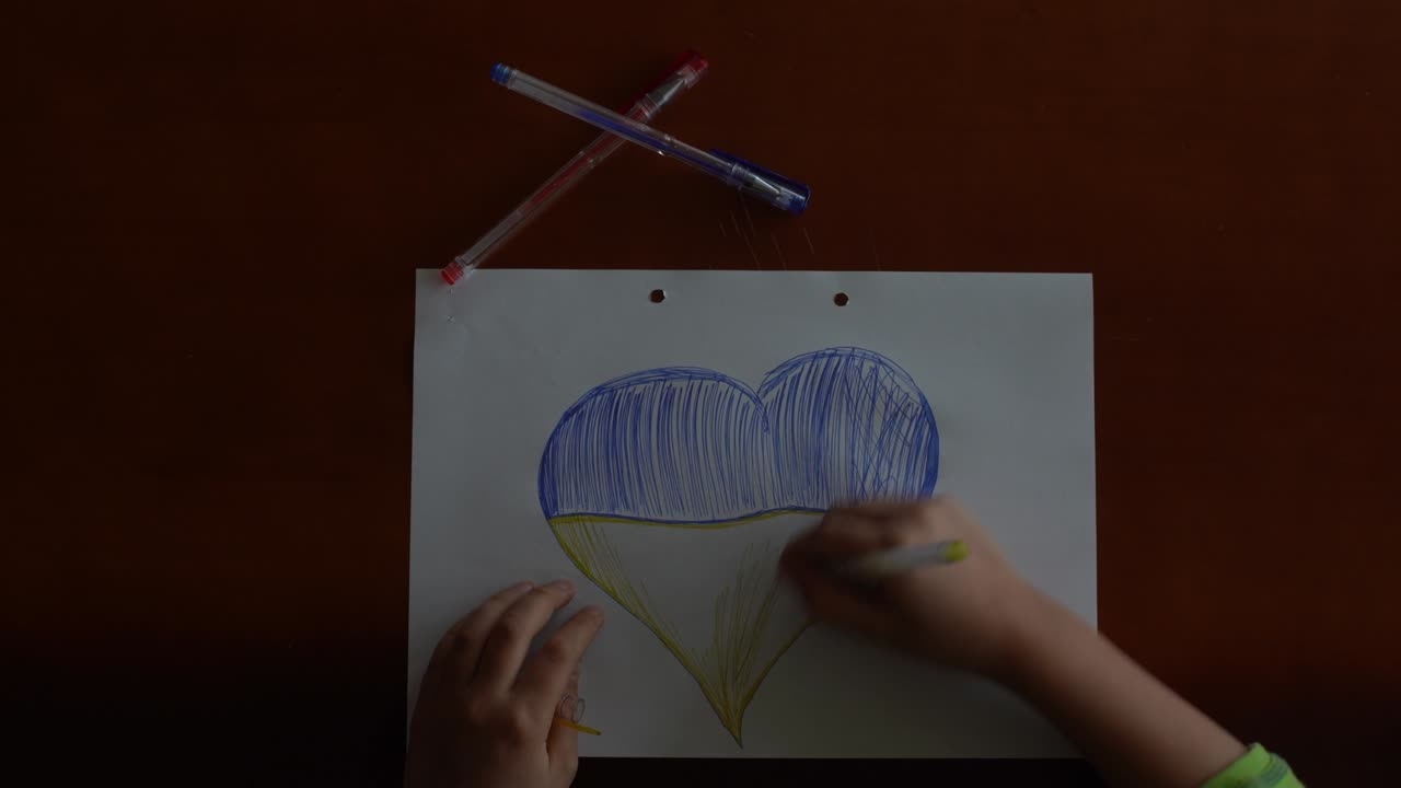 bandera ucraniana y un corazón en color amarillo y azul. el niño dibuja un corazón en la pizarra