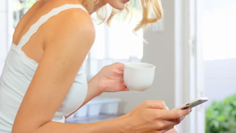 mujer bebiendo café y usando un teléfono inteligente