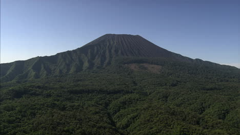 large volcano surrounded by lush forest under a clear blue sky