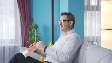 the man who has finished the book closes it and is lost in thought. he's happy.