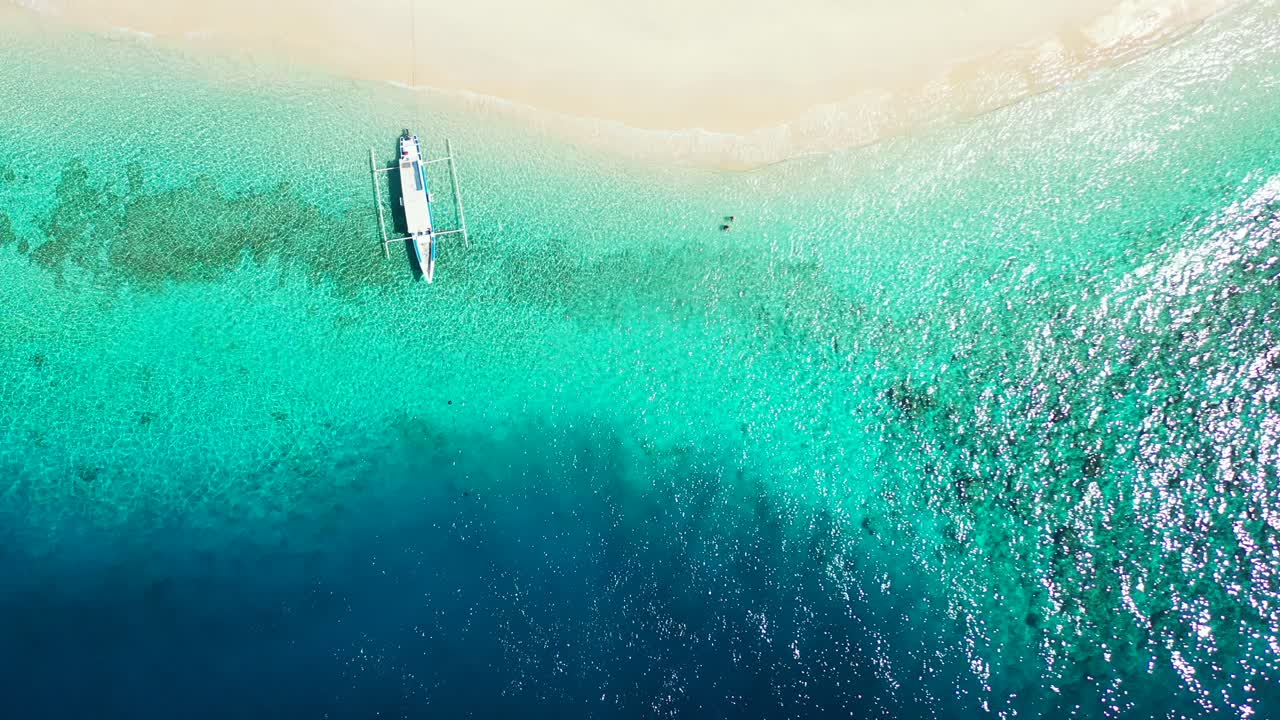 barco balinés jukung anclado en la costa de una isla tropical con una playa de arena blanca bañada por aguas tranquilas y cristalinas de una laguna turquesa