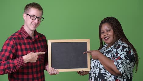 overweight african woman and young scandinavian man together against green background