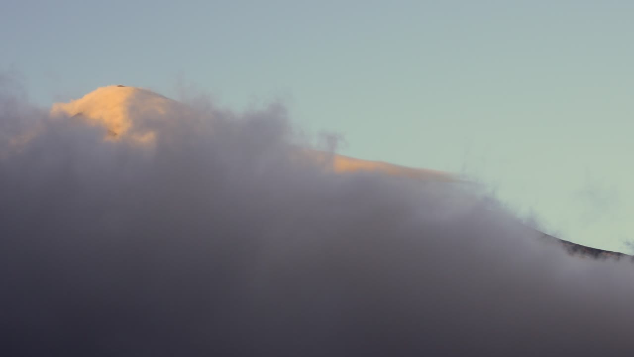 Static view of Lanin volcano summit with snow capped peak emerging above dense clouds, Neuquen, Patagonia, Argentina