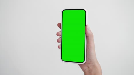 young person use smartphone with green screen chroma key close-up. girl hold in hand cell phone mock-up pov. concept watch and show internet social media, calls, read news, app, iot, e-shopping