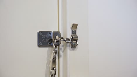 male hands locking a door chain lock