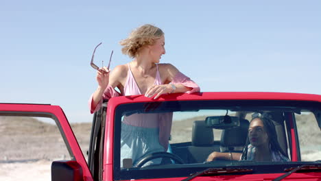 young caucasian woman stands by a red vehicle outdoors on a road trip