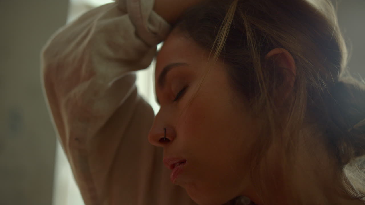 창의적인 여성이 실내에서 걸작을 창조합니다. 피곤한 화가가 이마를  ⁇ 고 있습니다.