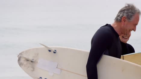 pareja jubilada caminando con tablas de surf