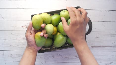 hands picking mangoes from a basket