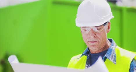 male engineer explaining while holding blueprint