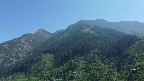 aerial view short of jibhi himachal pradesh in india. houses and trees in the mountainous area. faguli festival is one of the biggest festival in jibhi. the traditional houses here have stone roofs.