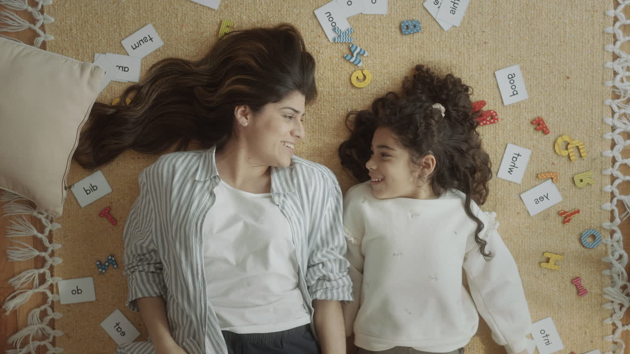 Happy Mother and Daughter Lying on the Floor and Waving at Camera