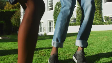 african american dad and son playing football together in the garden on a bright sunny day