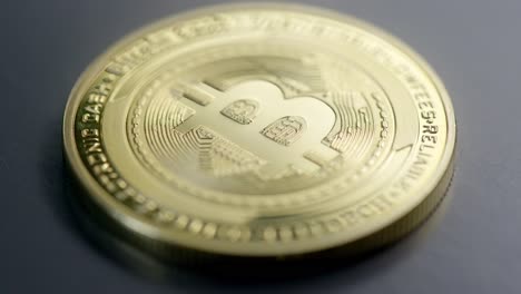 una moneda de bitcoin dorada física en la mesa oscura con un enfoque de rack - toma macro