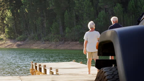 una pareja de ancianos blancos caminan por el muelle para admirar la vista del lago.