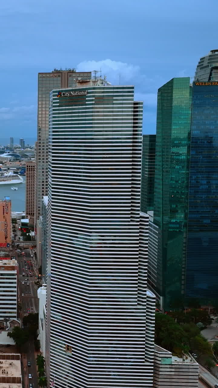 Drone flying along the building with glass balconies. Opening view to a harbor in Miami, Florida, USA. Vertical video