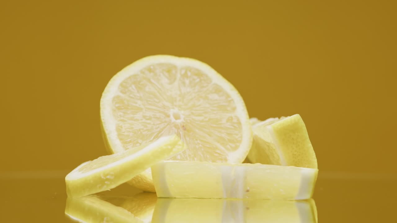 노란색 배경에 회전하는 익은 레몬 조각의 클로즈업, 호두 과일의 테일을 만드는, 차가운 레모네이드를 마시는, 신선한 잘라진 과일을 촬영하는